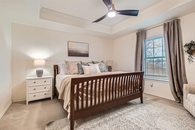 carpeted bedroom featuring ceiling fan, ornamental molding, and a tray ceiling