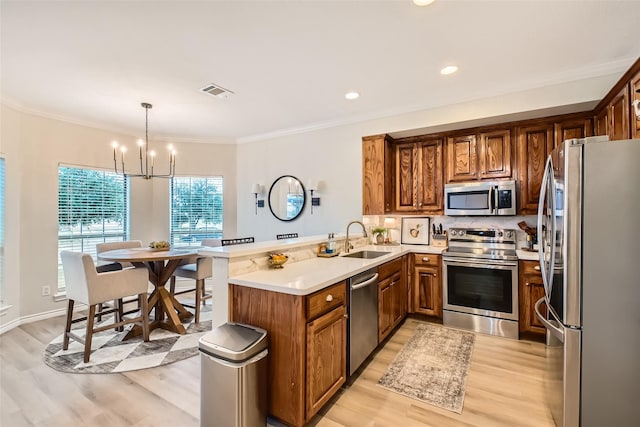 kitchen with sink, kitchen peninsula, stainless steel appliances, and hanging light fixtures