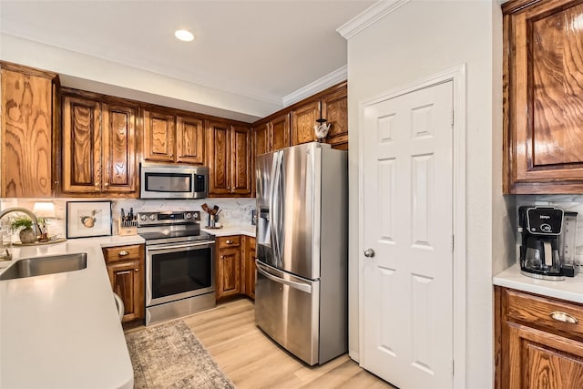 kitchen with sink, backsplash, stainless steel appliances, crown molding, and light hardwood / wood-style flooring