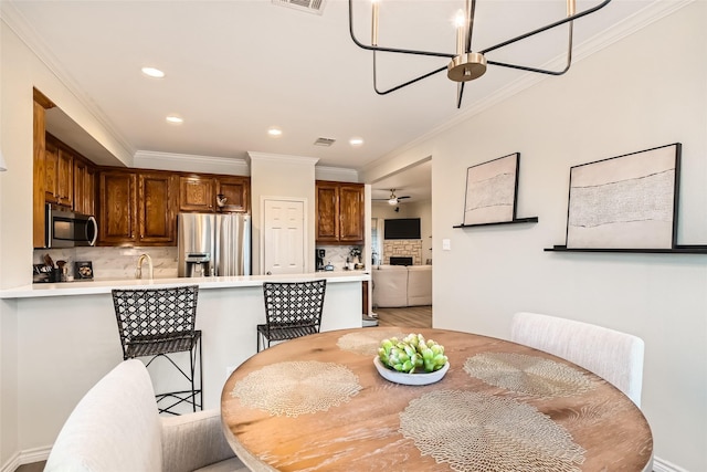 dining area featuring ceiling fan, ornamental molding, and sink