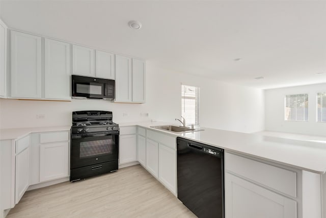 kitchen featuring white cabinetry, sink, kitchen peninsula, and black appliances