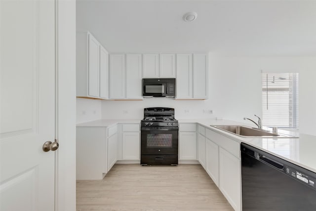 kitchen with sink, white cabinets, black appliances, and light wood-type flooring