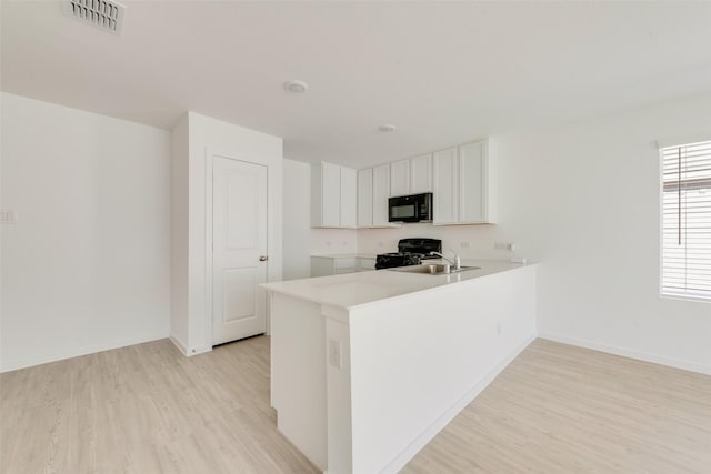 kitchen featuring white cabinets, black appliances, light hardwood / wood-style floors, sink, and kitchen peninsula