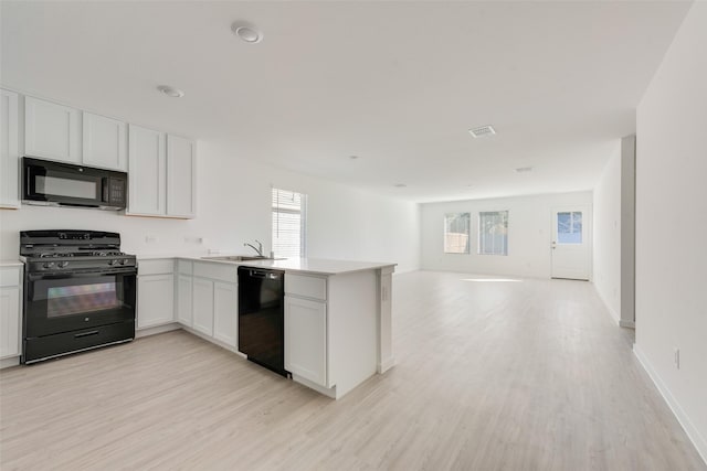 kitchen featuring light hardwood / wood-style flooring, white cabinets, kitchen peninsula, and black appliances