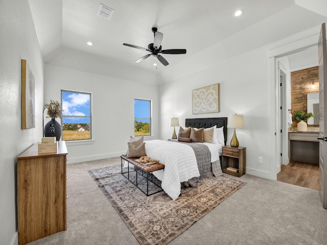 carpeted bedroom featuring ensuite bath, ceiling fan, and a raised ceiling