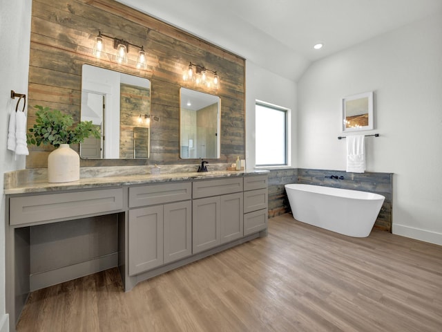 bathroom featuring vanity, a washtub, vaulted ceiling, and hardwood / wood-style flooring