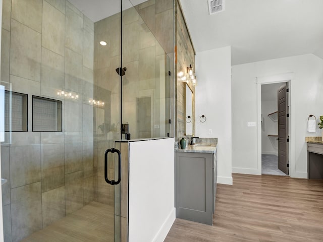 bathroom featuring wood-type flooring, walk in shower, and vanity