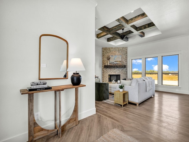 living room with beam ceiling, a fireplace, hardwood / wood-style floors, ornamental molding, and coffered ceiling