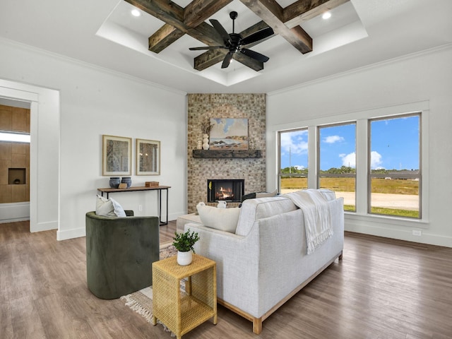 living room featuring wood-type flooring, a fireplace, ornamental molding, coffered ceiling, and beamed ceiling