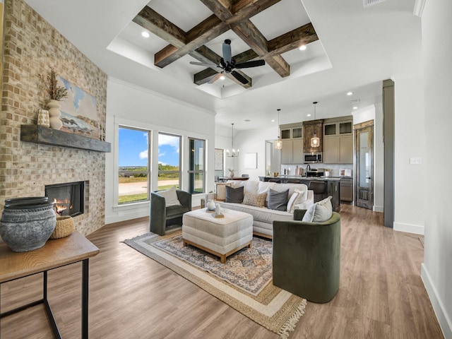 living room featuring hardwood / wood-style floors, a fireplace, coffered ceiling, beam ceiling, and ceiling fan with notable chandelier