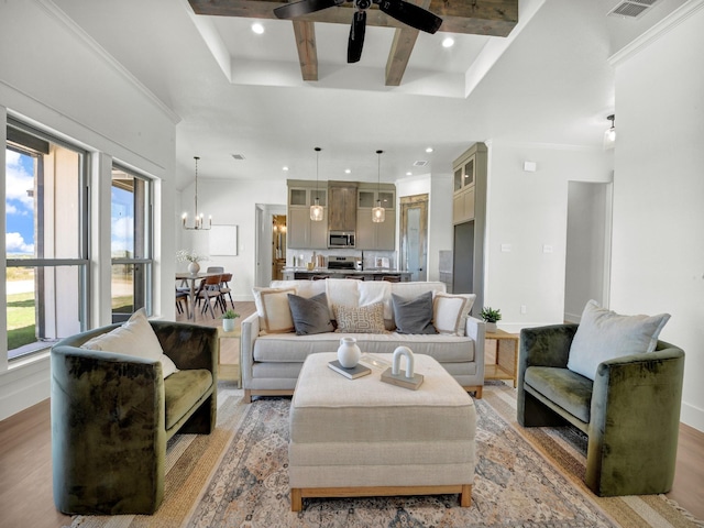 living room with crown molding, light hardwood / wood-style floors, and ceiling fan with notable chandelier