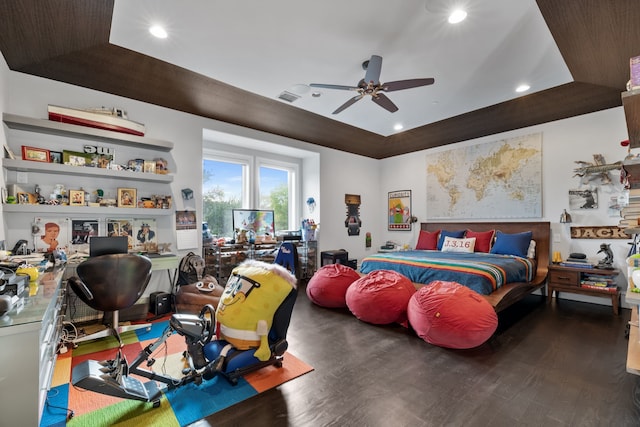 bedroom with ceiling fan, dark wood-type flooring, and a tray ceiling