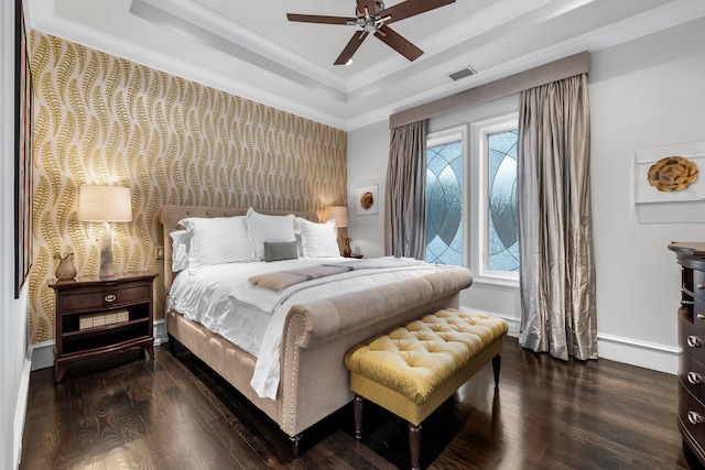 bedroom featuring baseboard heating, dark wood-type flooring, a raised ceiling, ceiling fan, and crown molding