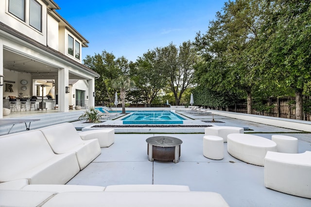 view of pool with an outdoor living space with a fire pit and a patio