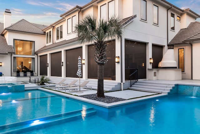 back house at dusk with a patio area and pool water feature