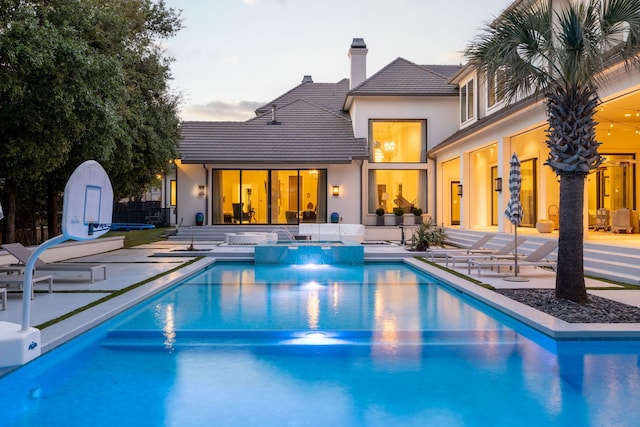 pool at dusk featuring a patio area