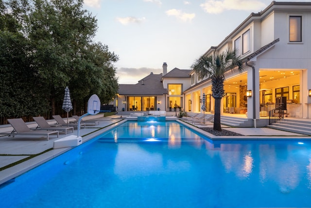 pool at dusk featuring a patio