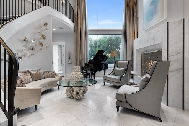 living room with a premium fireplace and a towering ceiling