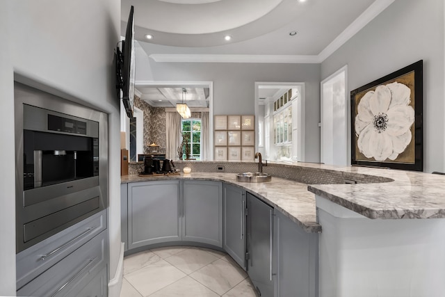 kitchen with sink, backsplash, gray cabinets, kitchen peninsula, and crown molding