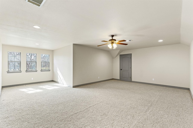 spare room with ceiling fan, light carpet, and vaulted ceiling