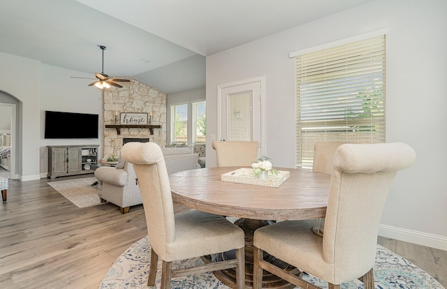 dining area with ceiling fan, wood-type flooring, lofted ceiling, and a fireplace