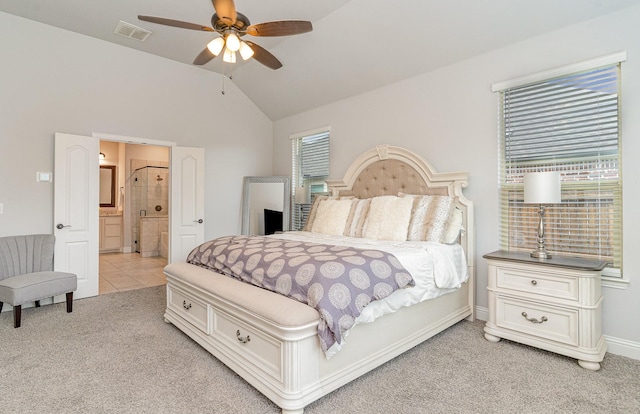 bedroom with ceiling fan, light colored carpet, connected bathroom, and vaulted ceiling