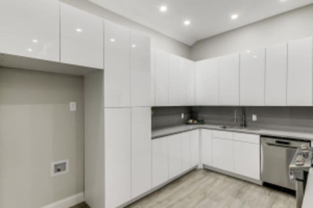 kitchen with light hardwood / wood-style floors, sink, white cabinetry, and stainless steel dishwasher