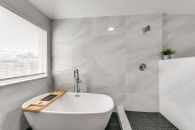 bathroom featuring tile patterned flooring, a bathtub, and a healthy amount of sunlight