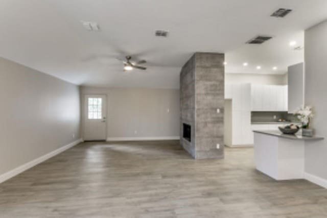 unfurnished living room featuring ceiling fan, a tile fireplace, and light hardwood / wood-style floors