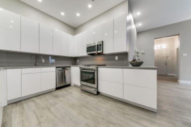 kitchen featuring appliances with stainless steel finishes, light hardwood / wood-style floors, and white cabinetry