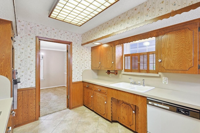 kitchen with light tile patterned floors, dishwasher, sink, and wooden walls