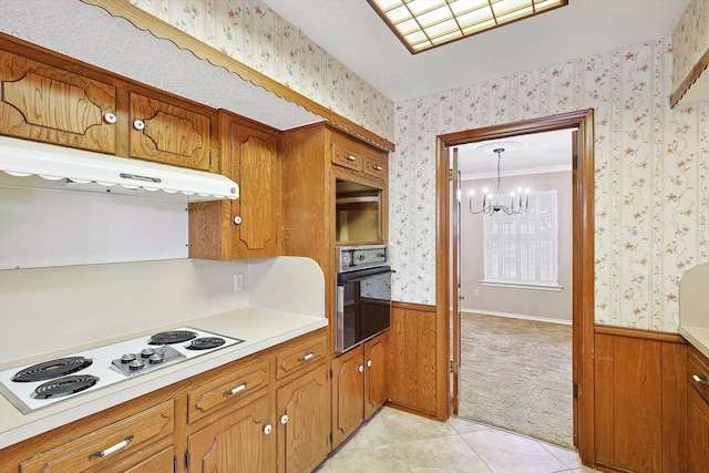 kitchen featuring wooden walls, decorative light fixtures, oven, white stovetop, and ornamental molding