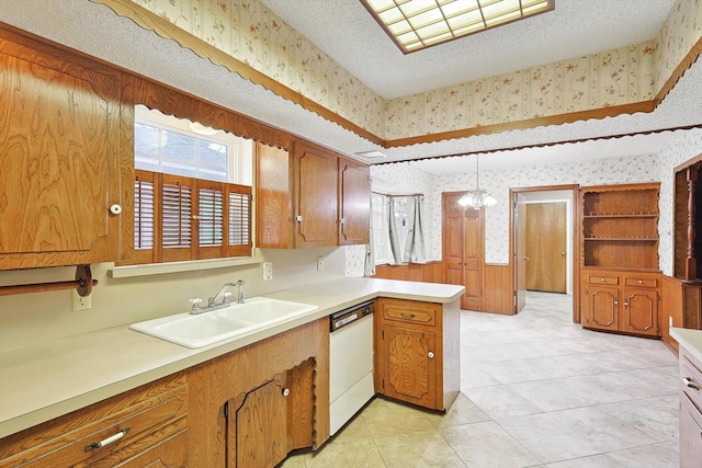 kitchen featuring kitchen peninsula, sink, white dishwasher, hanging light fixtures, and light tile patterned floors