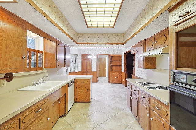 kitchen featuring dishwasher, black oven, sink, cooktop, and kitchen peninsula