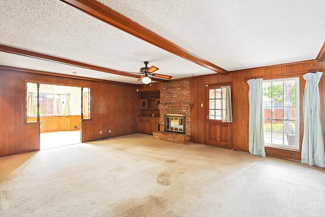 unfurnished living room featuring beam ceiling, light carpet, a fireplace, and a textured ceiling