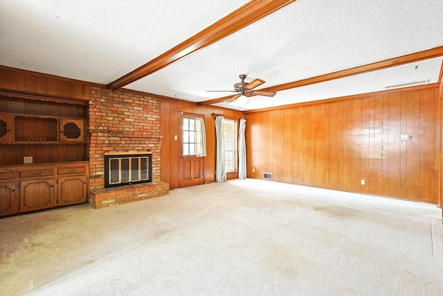 carpeted living room with a textured ceiling, wood walls, beamed ceiling, and a fireplace