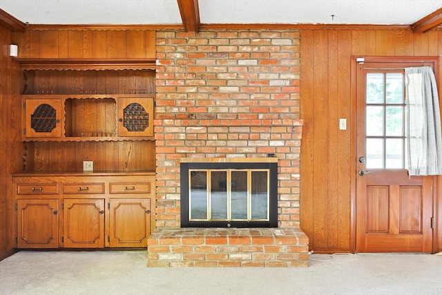 living room featuring beam ceiling, light colored carpet, wood walls, and a brick fireplace