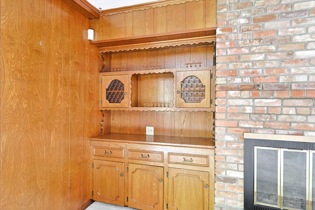 room details featuring a brick fireplace, crown molding, and wood walls