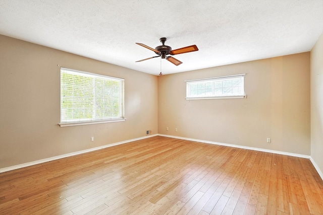 spare room featuring light wood-type flooring, ceiling fan, and a textured ceiling