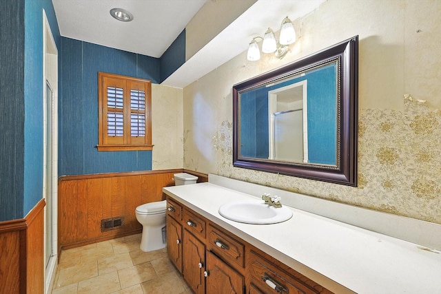 bathroom with toilet, vanity, and wood walls