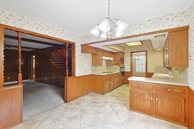 kitchen featuring oven, a chandelier, hanging light fixtures, and sink