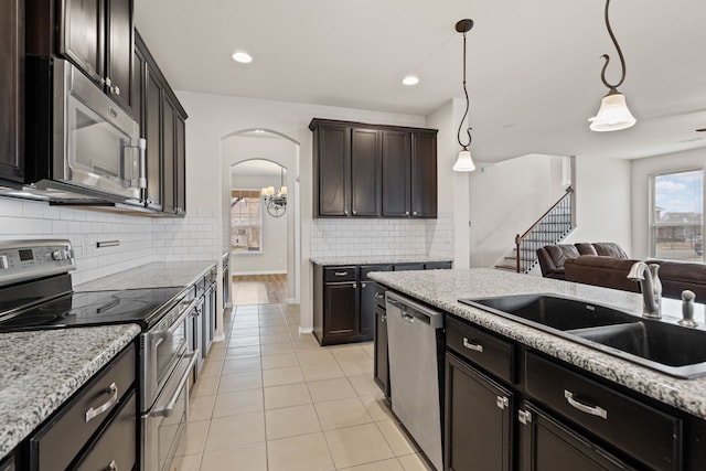 kitchen featuring sink, decorative light fixtures, dark brown cabinets, light tile patterned floors, and stainless steel appliances