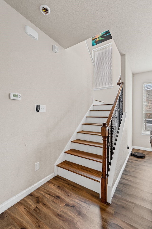 staircase featuring hardwood / wood-style floors and a textured ceiling