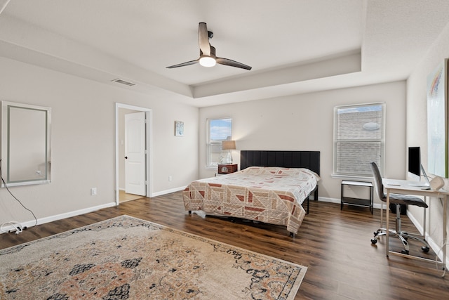 bedroom featuring a tray ceiling, dark hardwood / wood-style floors, and ceiling fan