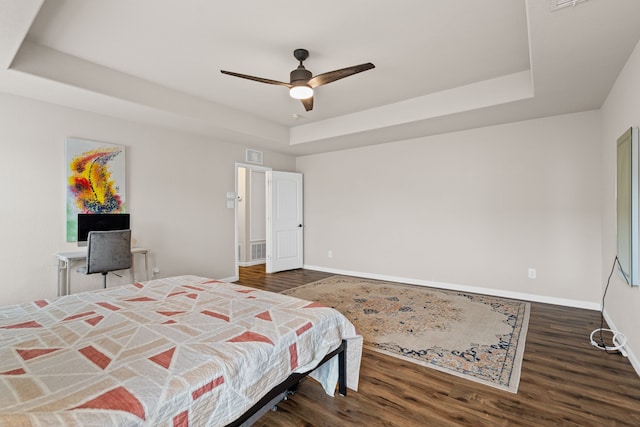 bedroom featuring dark hardwood / wood-style flooring, a raised ceiling, and ceiling fan