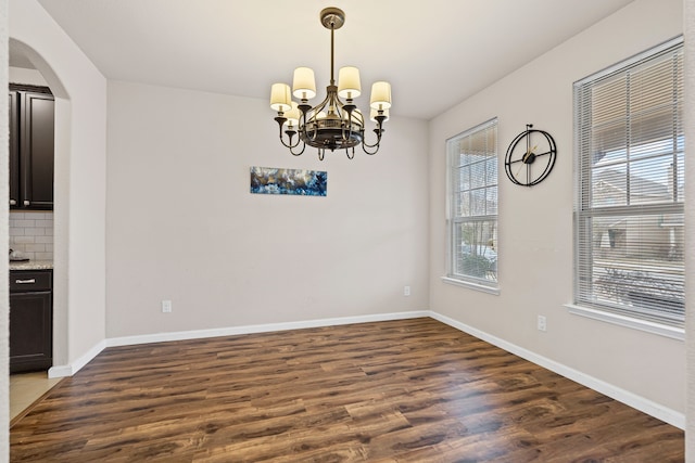 unfurnished dining area with dark hardwood / wood-style flooring and a notable chandelier