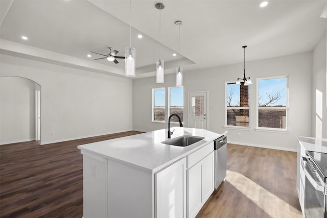 kitchen with white cabinets, appliances with stainless steel finishes, decorative light fixtures, an island with sink, and sink