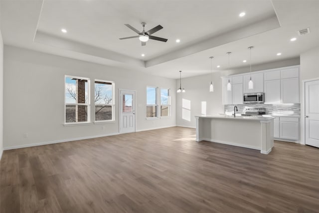 kitchen featuring a raised ceiling, white cabinets, hanging light fixtures, and stainless steel appliances