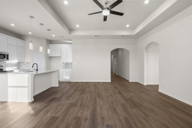 kitchen featuring decorative backsplash, white cabinets, and an island with sink