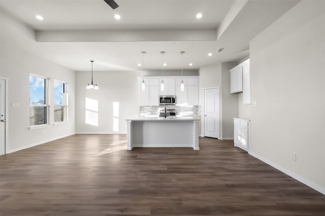 kitchen with white cabinets, decorative light fixtures, dark wood-type flooring, stainless steel appliances, and an island with sink